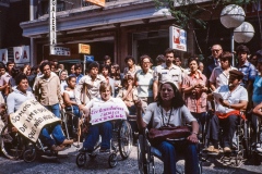 Grupo de pessoas em frente ao Teatro Municipal de SP com o cartaz do "Ano Internacional das Pessoas Deficientes". 7/4/1981. Coleção Romeu Sassaki.