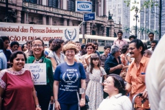 Grupo de pessoas em frente ao Teatro Municipal de SP com o cartaz do "Ano Internacional das Pessoas Deficientes". 7/4/1981. Coleção Romeu Sassaki.