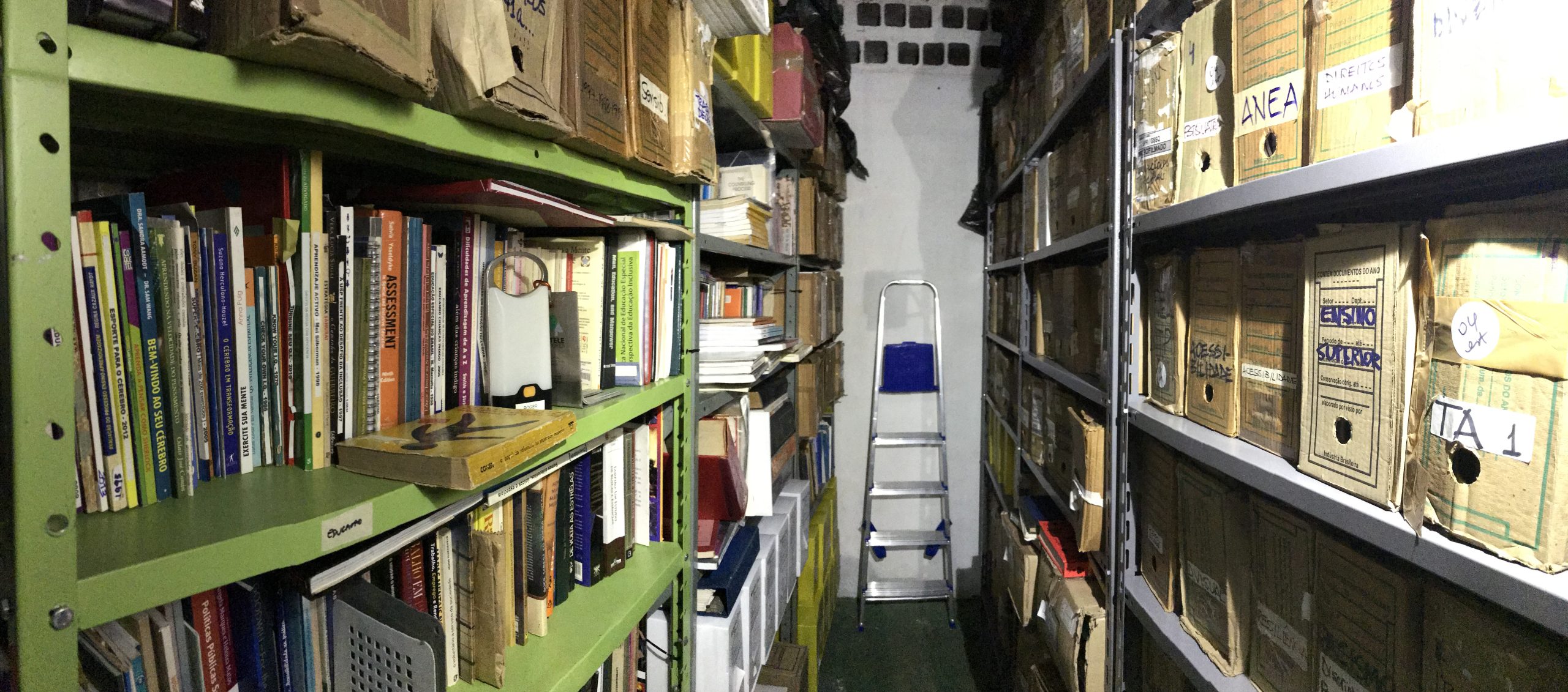 Fotografia das estantes cheias de documentos de Romeu Sassaki em depósito apertado.